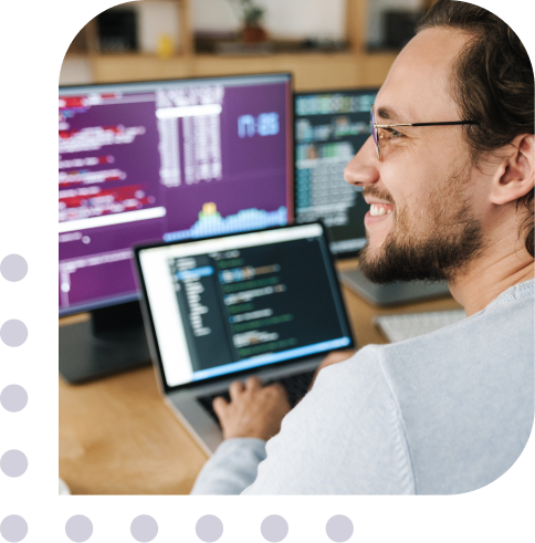 man smiling in front of laptop doing some coding