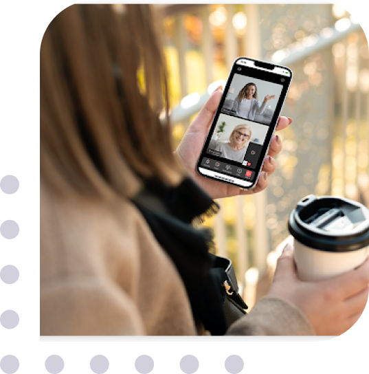 woman holding a cup of coffee while having a video call on phone with colleague